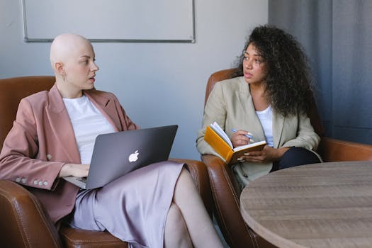 Two diverse businesswomen having a discussion in a modern office setting.