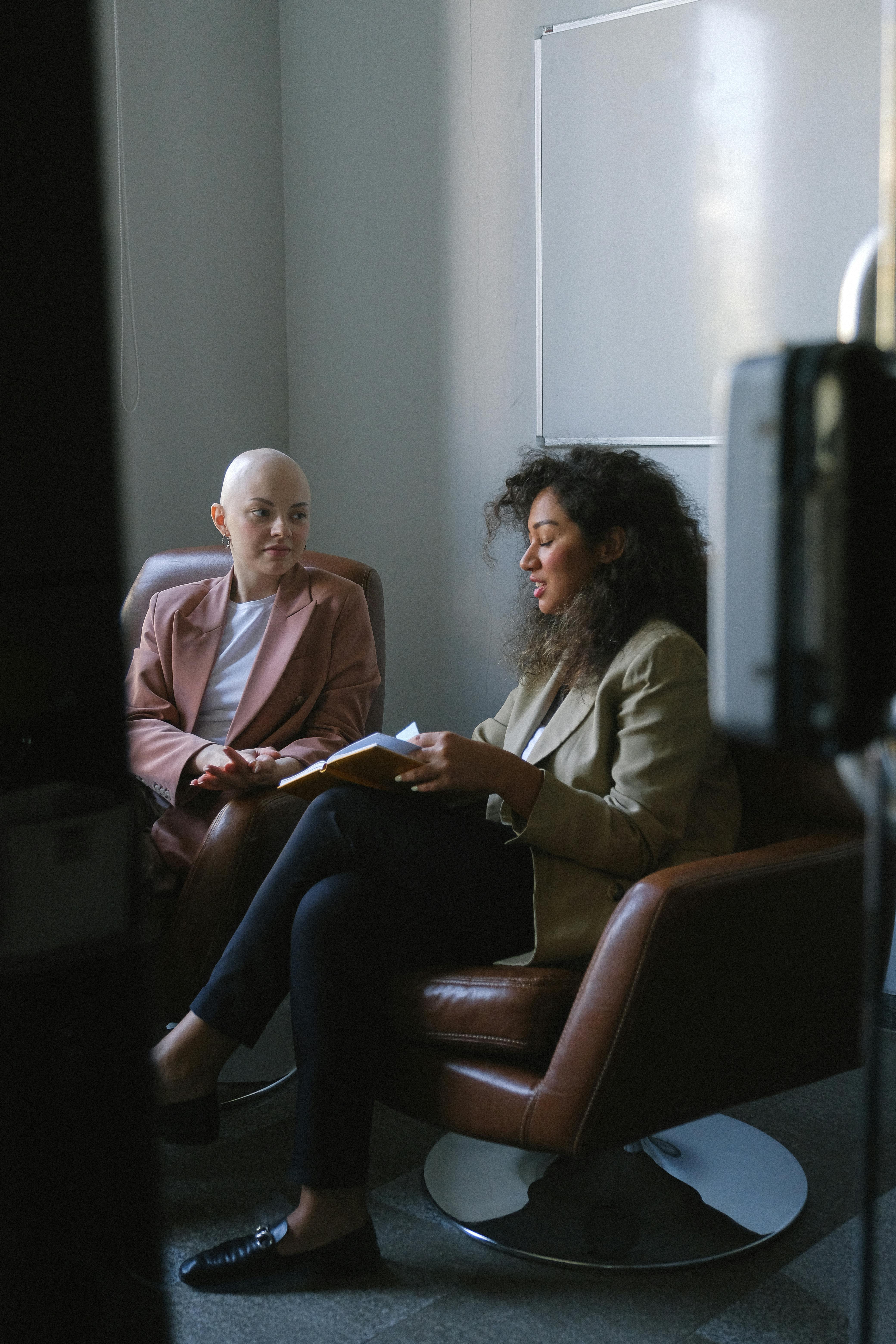 multiethnic female coworkers sitting in conference hall and communicating