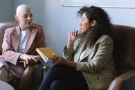 Young female friends having conversation sitting in armchairs in room