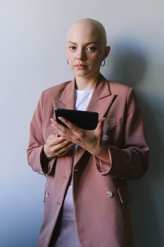 一位穿着粉色西装外套的秃头女商人在室内使用数字平板电脑