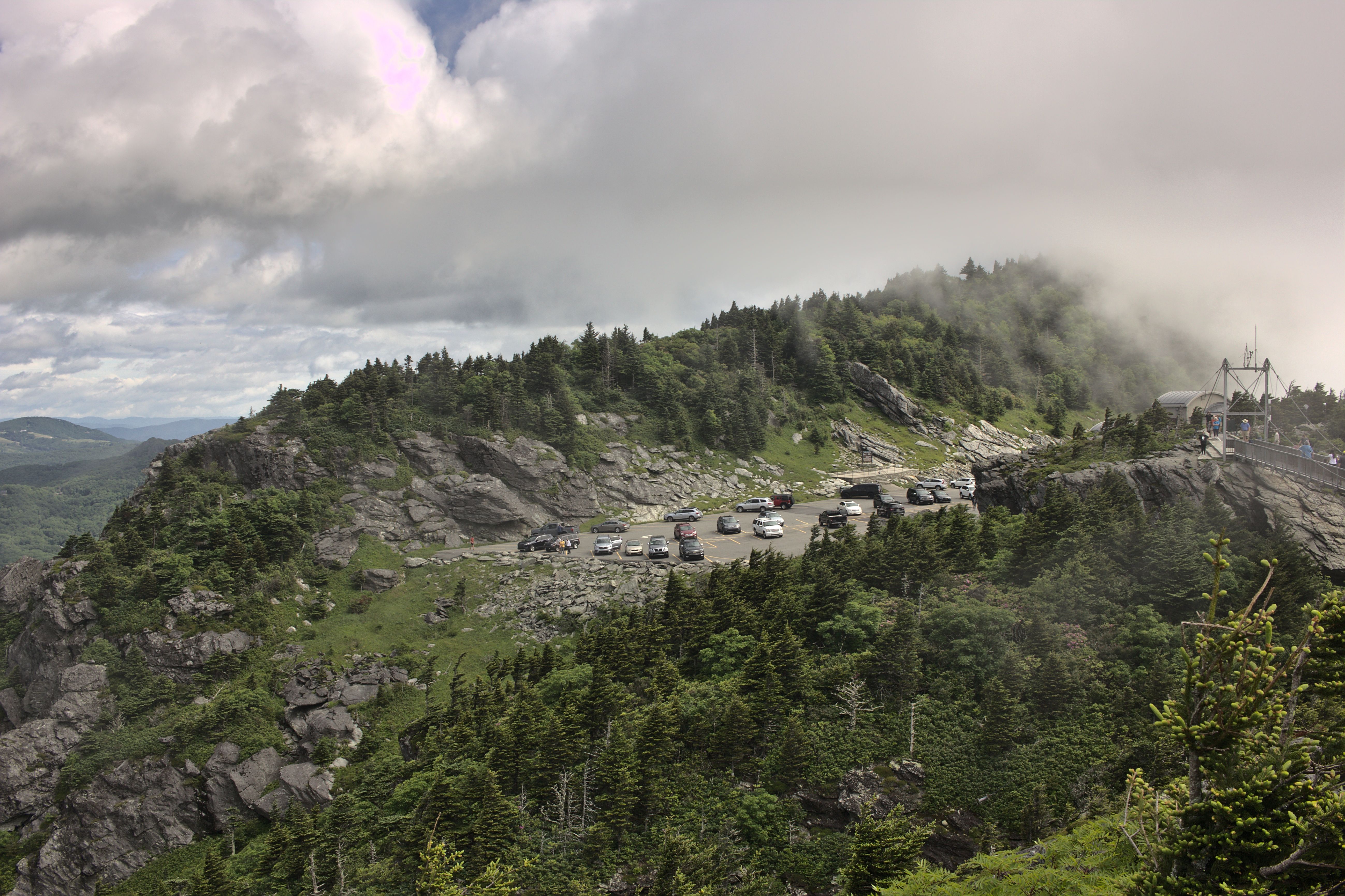 A foggy mountain overlook with a road winding through rugged terrain