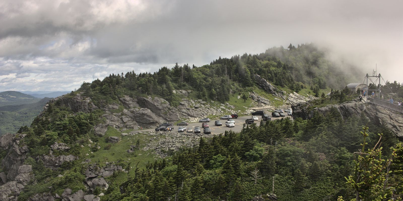A foggy mountain overlook with a road winding through rugged terrain