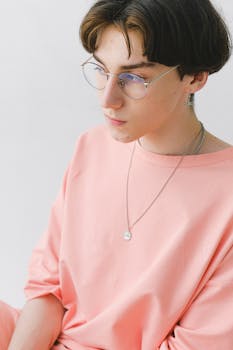 A trendy teen wearing pink looks thoughtfully away in a modern studio setting.