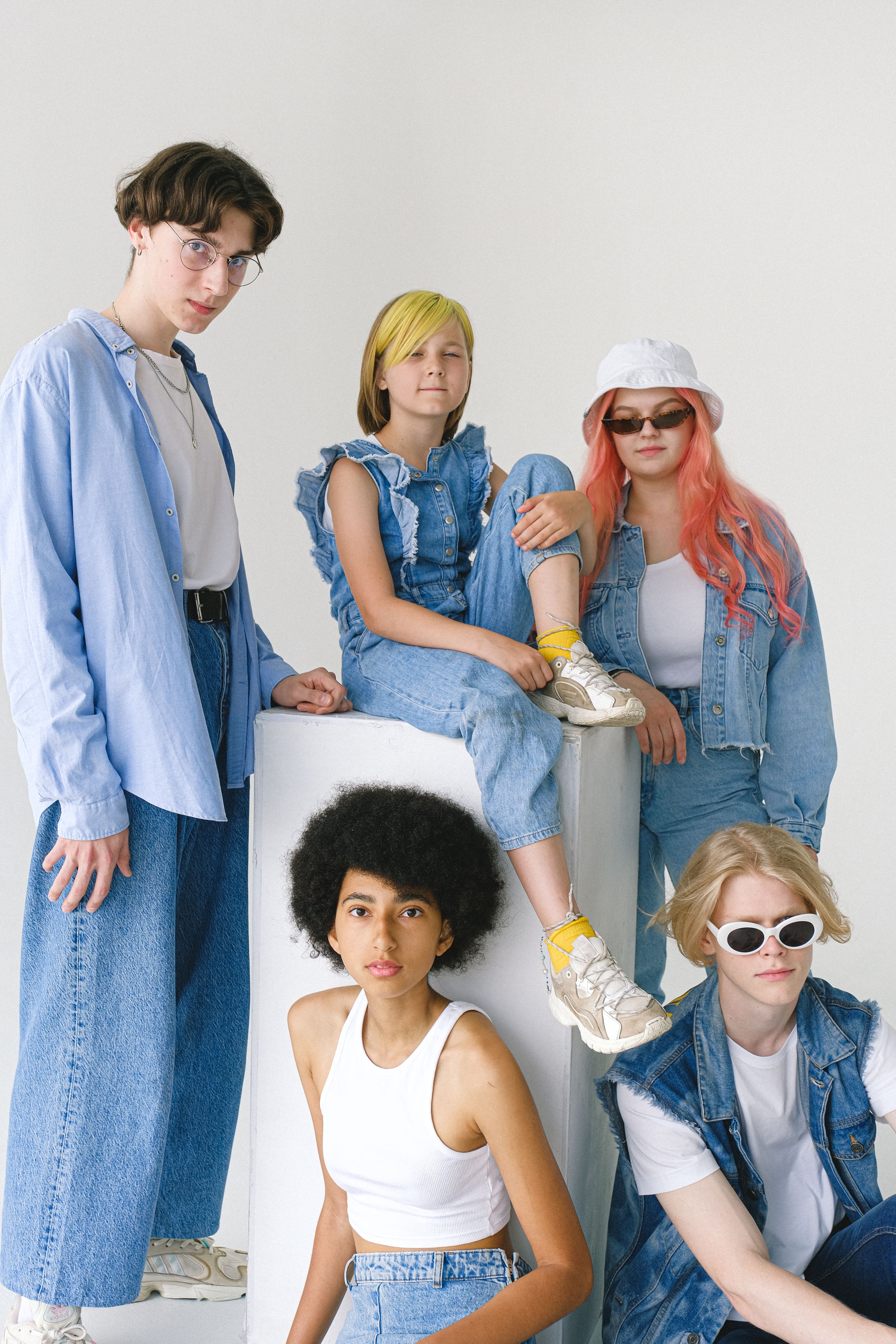 Um grupo diverso de jovens adultos exibindo roupas de denim modernas em um estúdio.