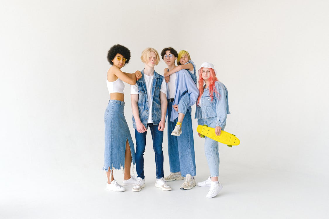 Free Full body group of teenager friends in jeans wear and glasses with yellow penny board on white background looking at camera Stock Photo