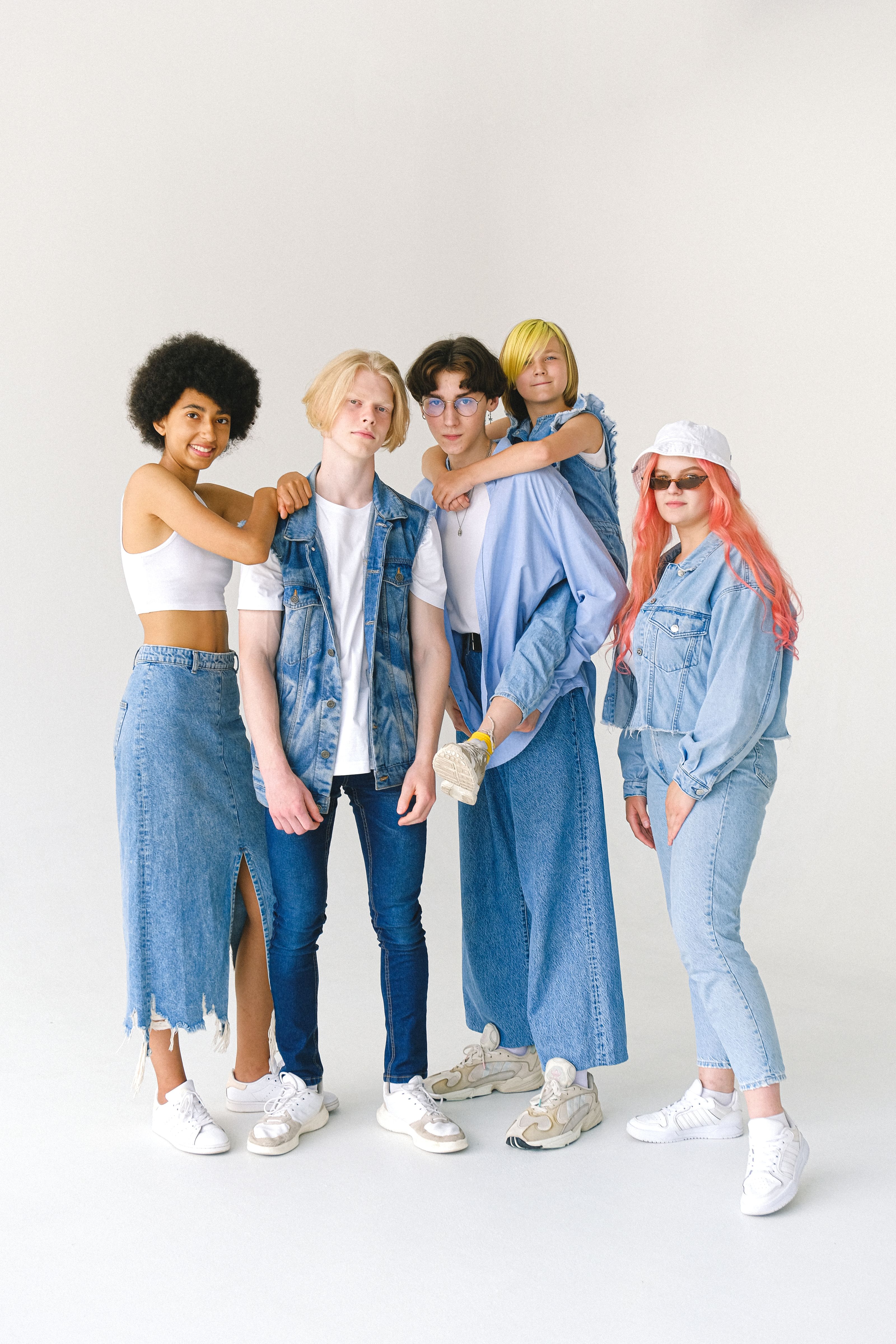 Um grupo estiloso e diverso de jovens posando com confiança em moda denim contra um fundo branco.