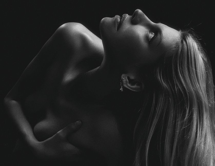 A captivating black and white studio portrait of a woman in a seductive pose.