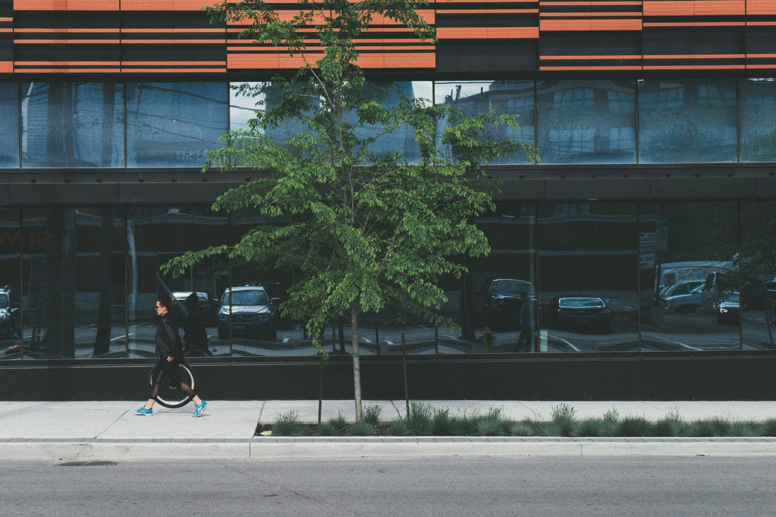 A person walking past the glazed facade of a city building — photo by Scott Webb on Pexels