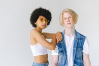 Young multiracial couple in denim and white wear on white background looking at camera