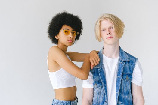 Young multiracial couple in denim and white wear on white background looking at camera