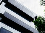 低角度视角下的现代摩天大楼，其几何玻璃立面映照着多云的天空