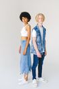 Full body serious multiracial young couple standing against white background and looking at camera