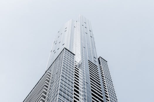 从低角度拍摄，一座具有几何玻璃立面的现代摩天大楼引人注目