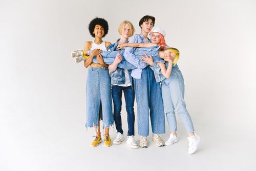 Free Full body of multiethnic teenagers and schoolchild in casual denim outfit standing in studio and holding kid on hands on white background Stock Photo