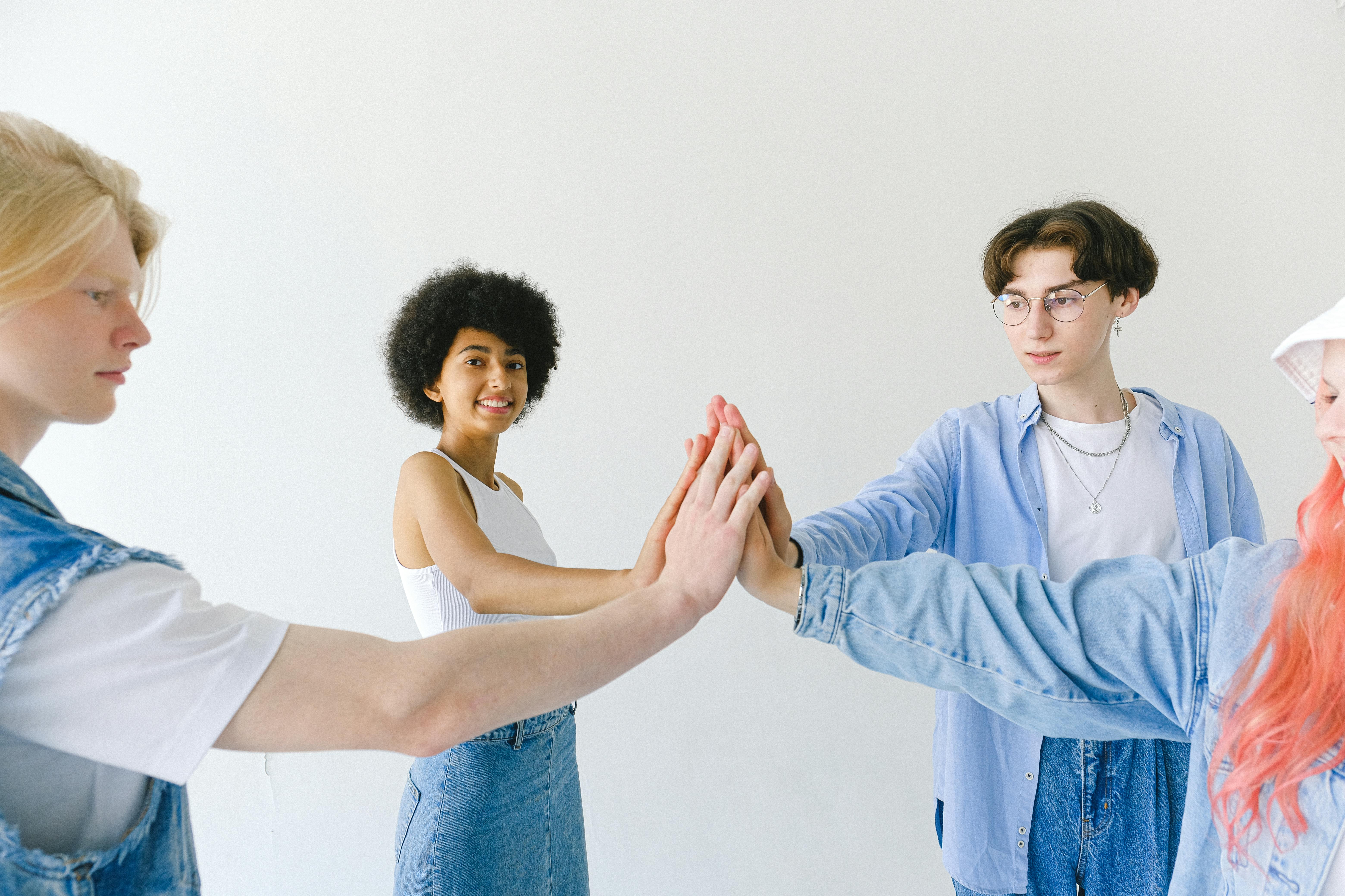 positive friends with hands stacked on white background