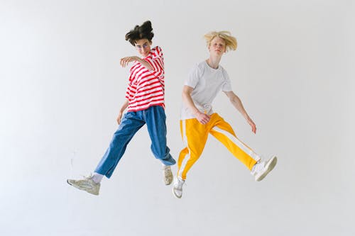 Cheerful friends jumping above floor and looking at camera