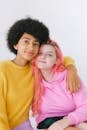 Diverse cheerful teenage girls looking at camera in bright yellow sweater and pink hoodie on white background