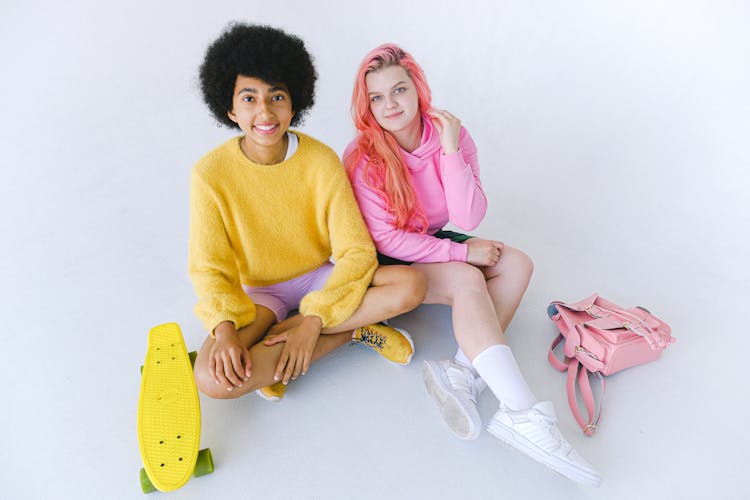 Delighted Multiethnic Teenage Girls With Skateboard And Stylish Backpack