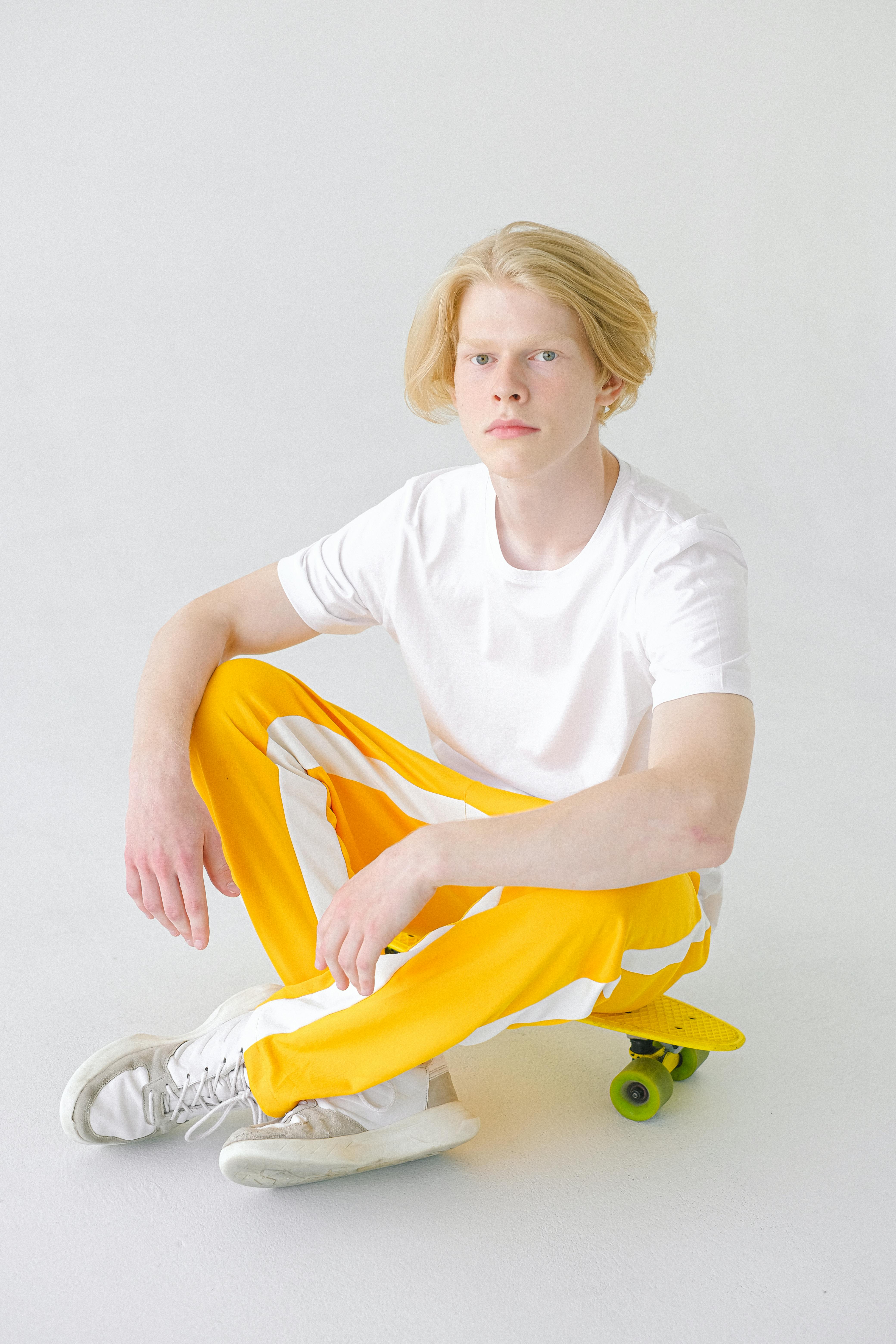 teenager in bright yellow trousers resting on skateboard