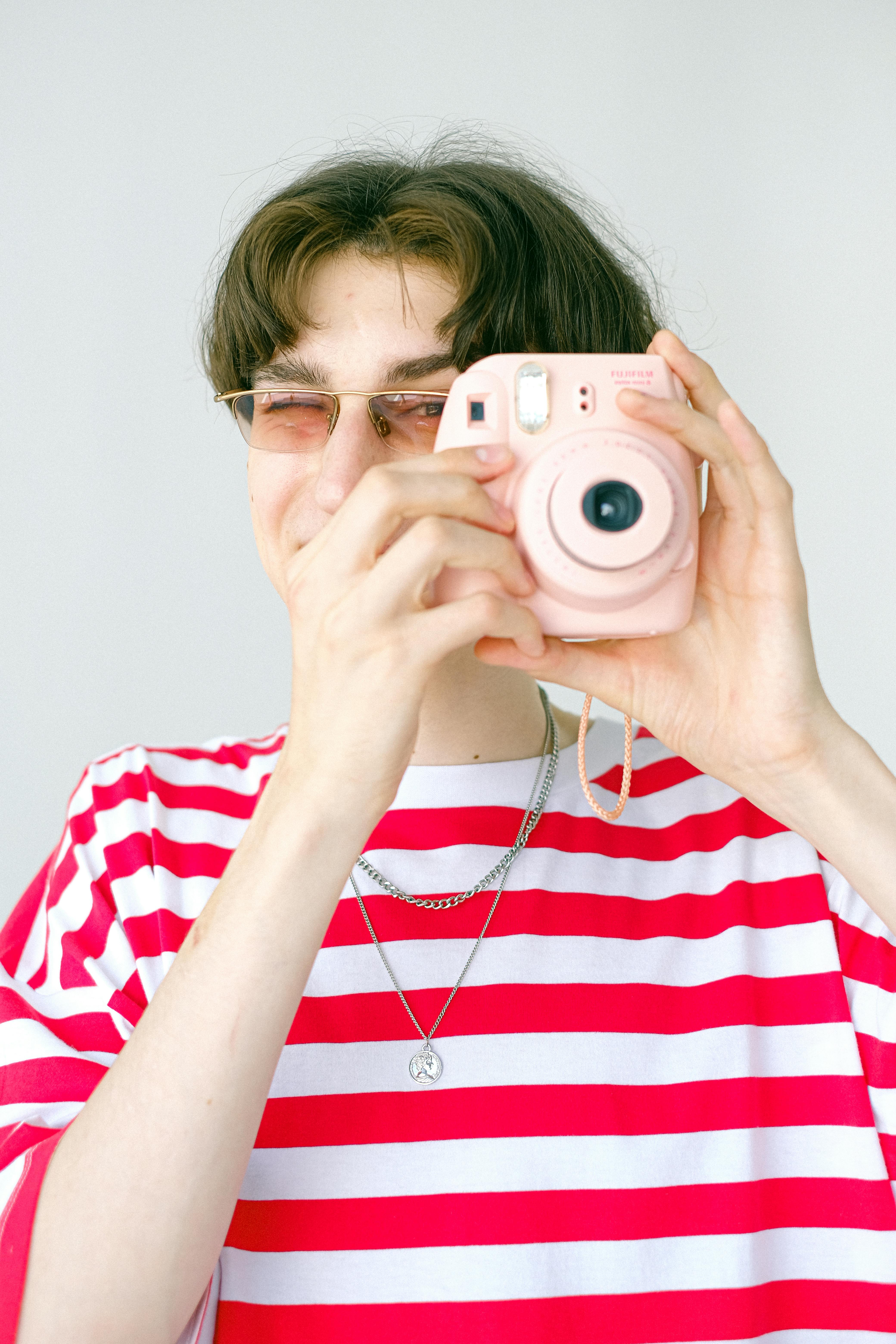 stylish teenage boy taking photo with instant camera