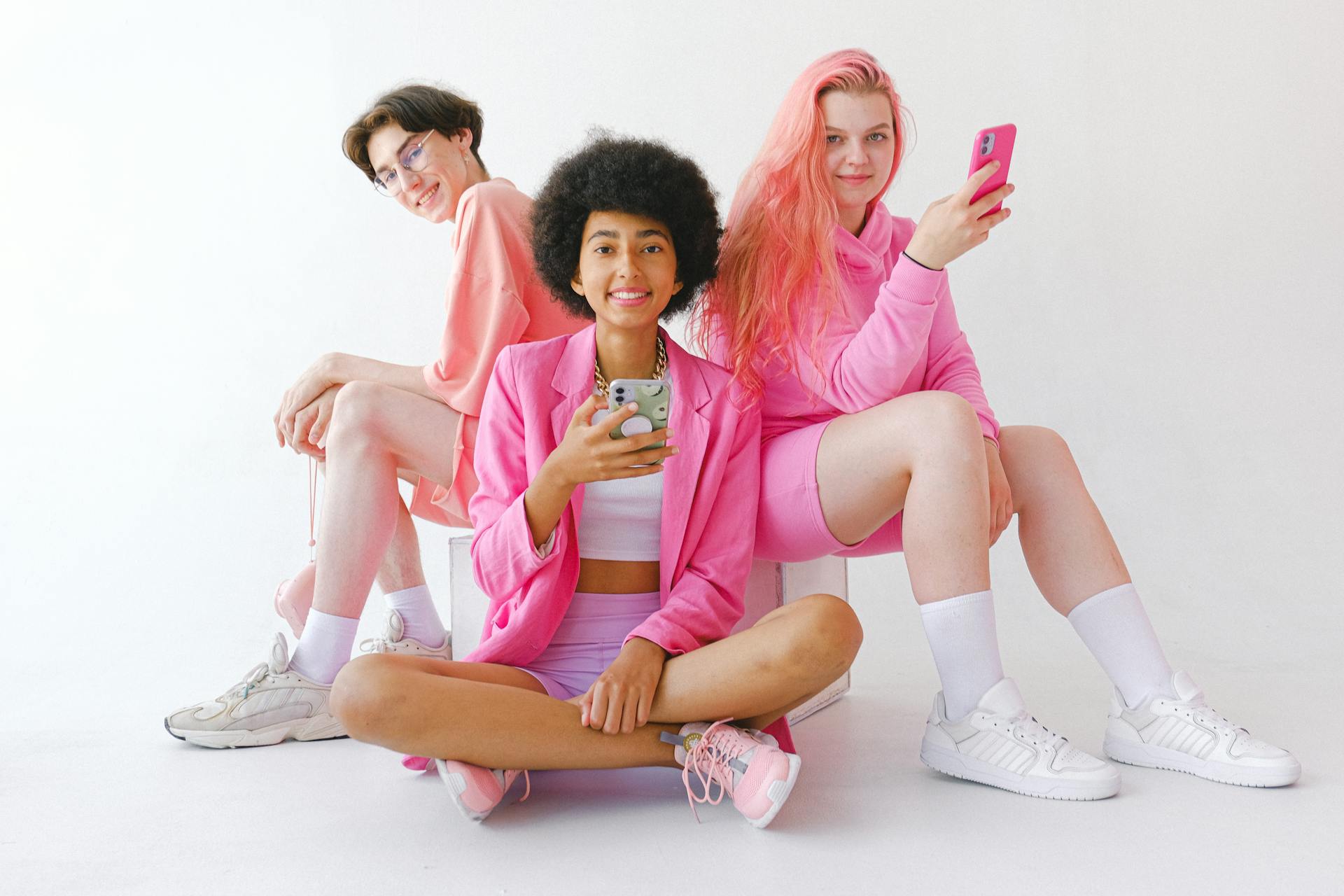 Cheerful multiracial teenagers in trendy outfit with smartphones