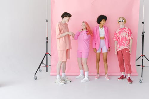 Full body of diverse teenage friends talking and smiling in professional photo studio with special equipment