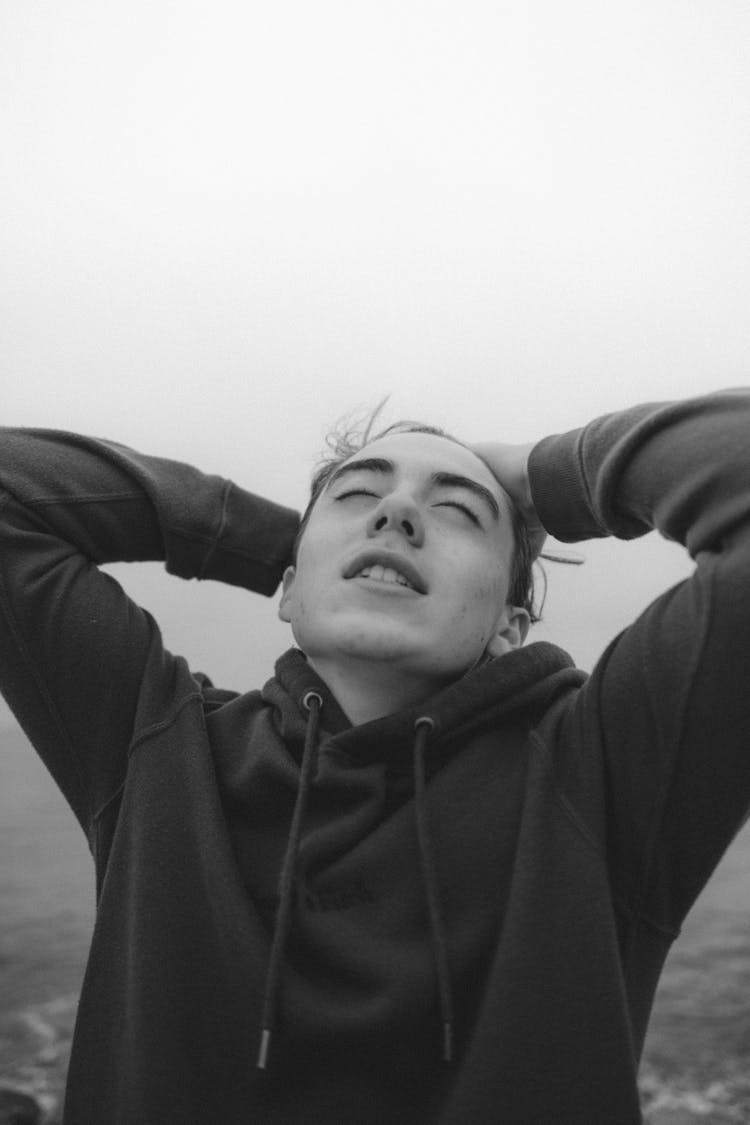 Dreamy Man Touching Head Against Sea Under White Sky