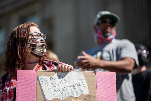 Free Anonymous female in eyeglasses and protective mask standing with cardboard in hands during demonstration against injustice with blurred man on background Stock Photo
