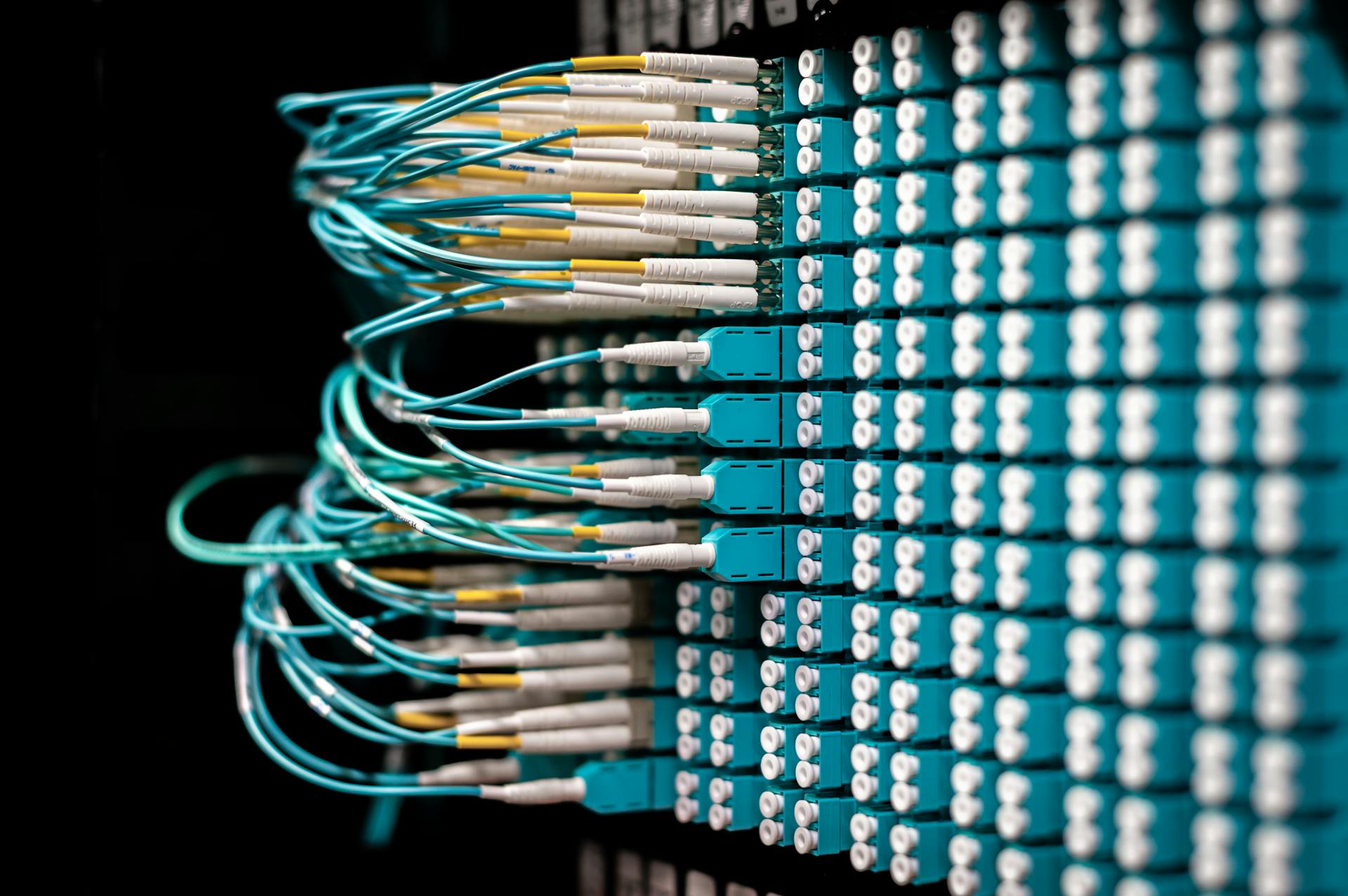 Server with electronic switches and connectors with yellow and green wires plugged in plastic device in operating room on black background