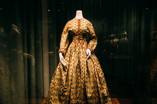 Through glass view of colorful elegant old style feminine costume on mannequin on exhibition
