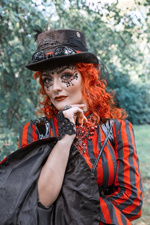 A Woman in Striped Blouse and Black Hat Seriously Looking at the Camera while Her Hand is on Her Chin