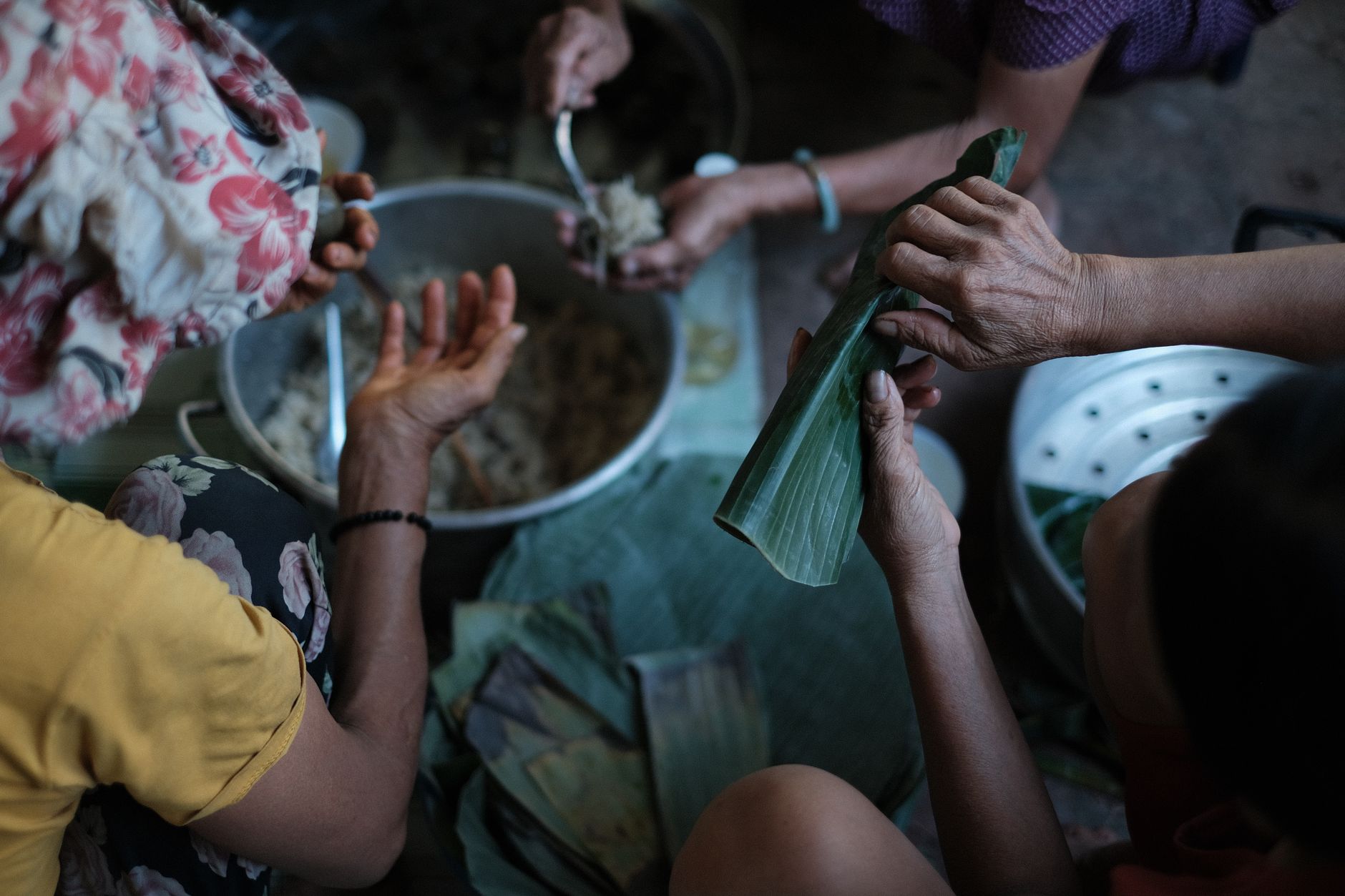 Group making traditional Vietnamese banh it with banana leaves in a cultural setting.