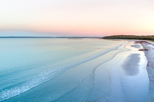 Песчаный берег возле волнистого океана на закате