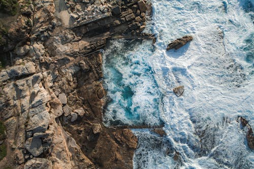 Rough rock near foamy sea in stormy weather