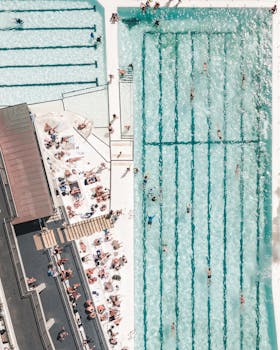 Explore the vibrant energy at Bondi Beach with stunning aerial views of swimming pools and sunbathers.