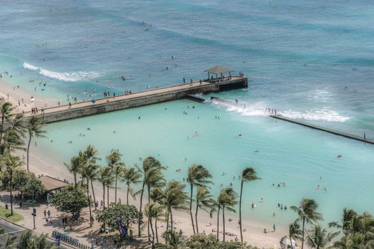 From above of people resting on tropical sandy beach and swimming in wavy sea in sunny day