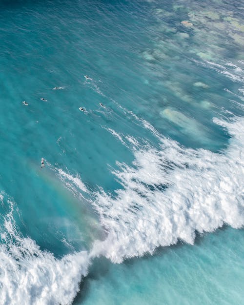 Aerial view of bright blue water of sea with foamy waves in sunny day