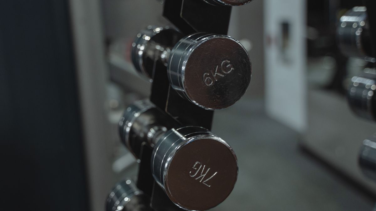 Metal dumbbells neatly arranged in a gym setting, ideal for fitness enthusiasts.