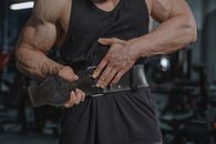 Man in Black Tank Top Holding Black Metal Bar