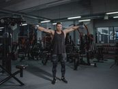 Man in Black Tank Top and Black Pants Standing on Gray Carpet