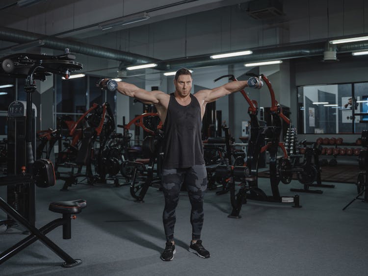 Man Lifting Dumbbells Inside A Gym 