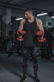 Strong man lifting dumbbells in a gym, showcasing fitness and muscle strength.