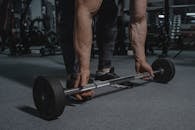 Man in Black Pants and Black Leather Shoes Holding Black Barbell