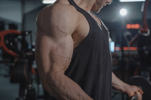 A detailed view of a muscular arm and veins in a gym environment, focusing on strength.