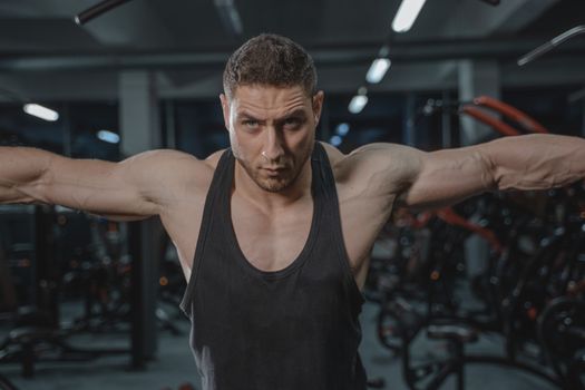 Focused man in activewear exercising in a gym environment.