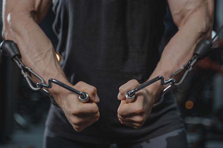 A Person Stretching His Arms Using Metal Chain