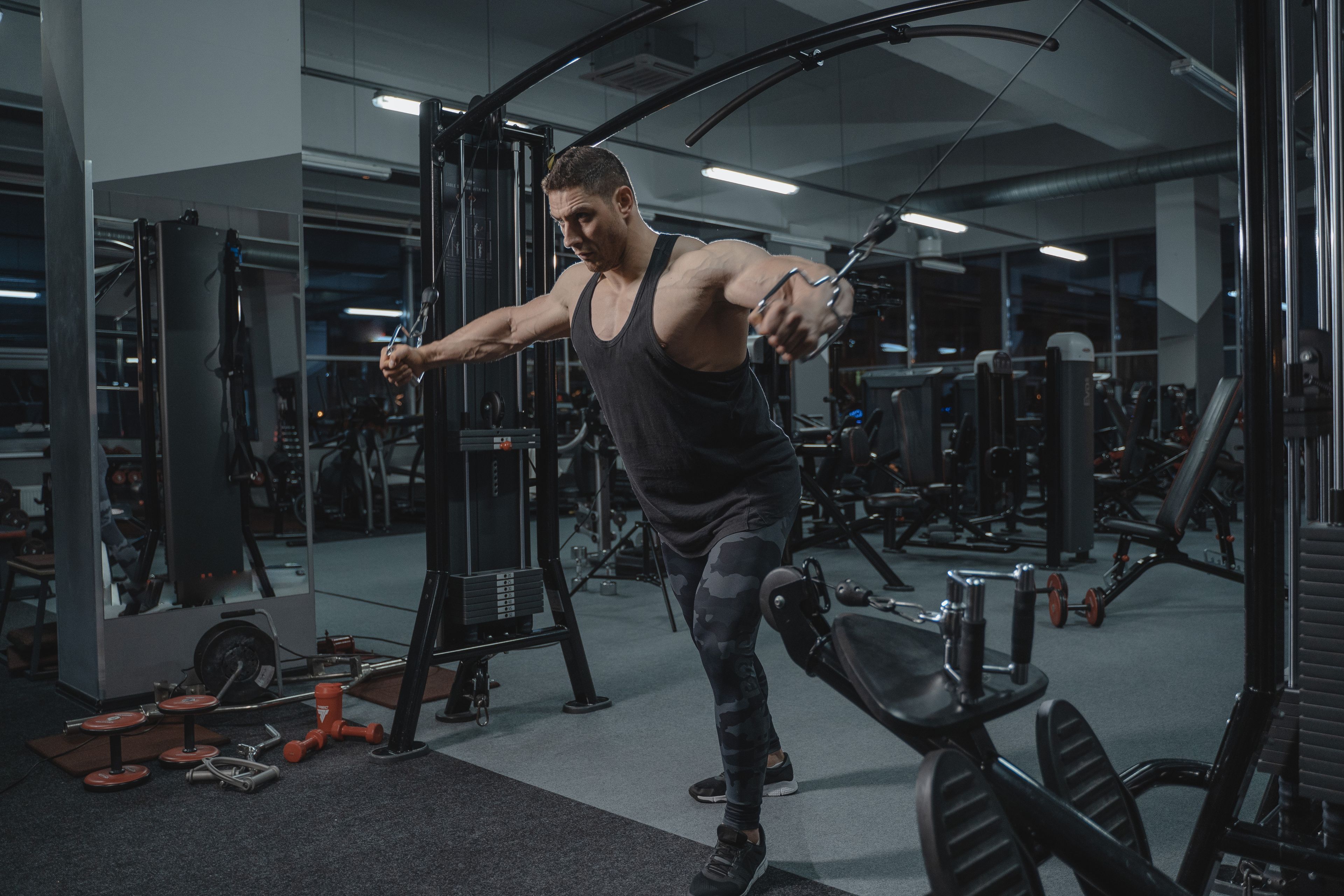 Muscular man working out in the gym using a cable crossover machine.
