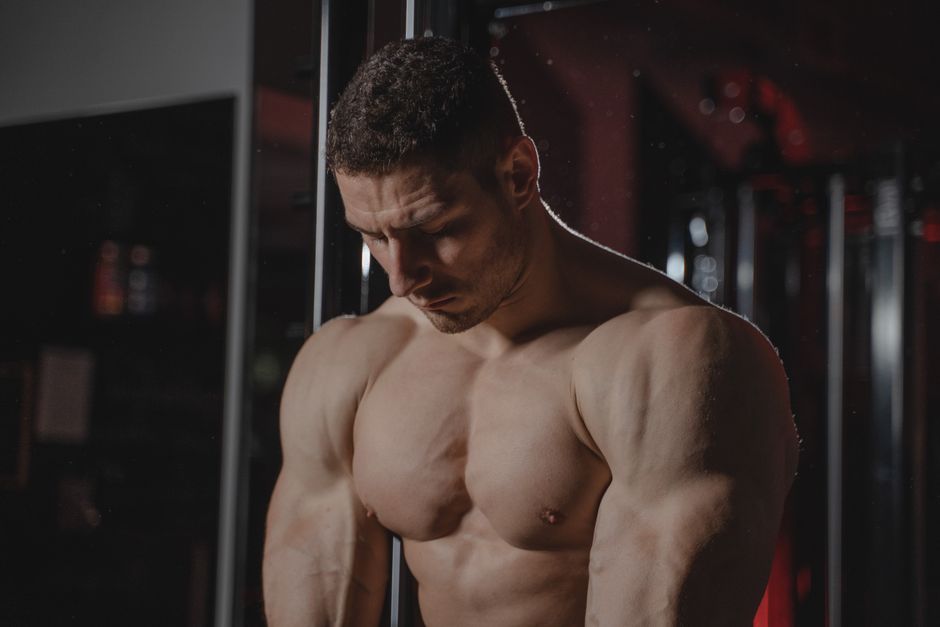 Strong, muscular man flexing in an indoor gym setting, showcasing strength and determination.