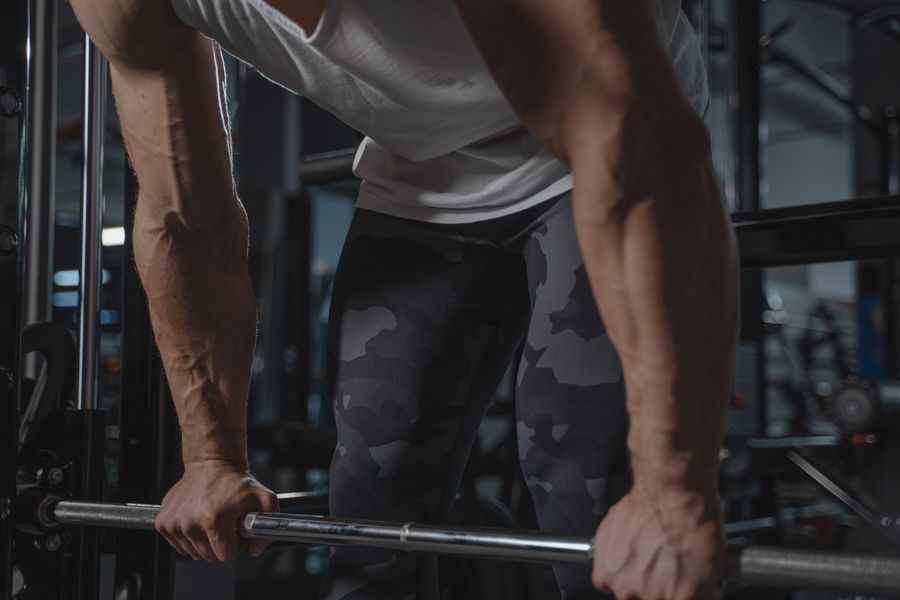 Athlete gripping a barbell in a dim gym, photo by Tima Miroshnichenko on Pexels