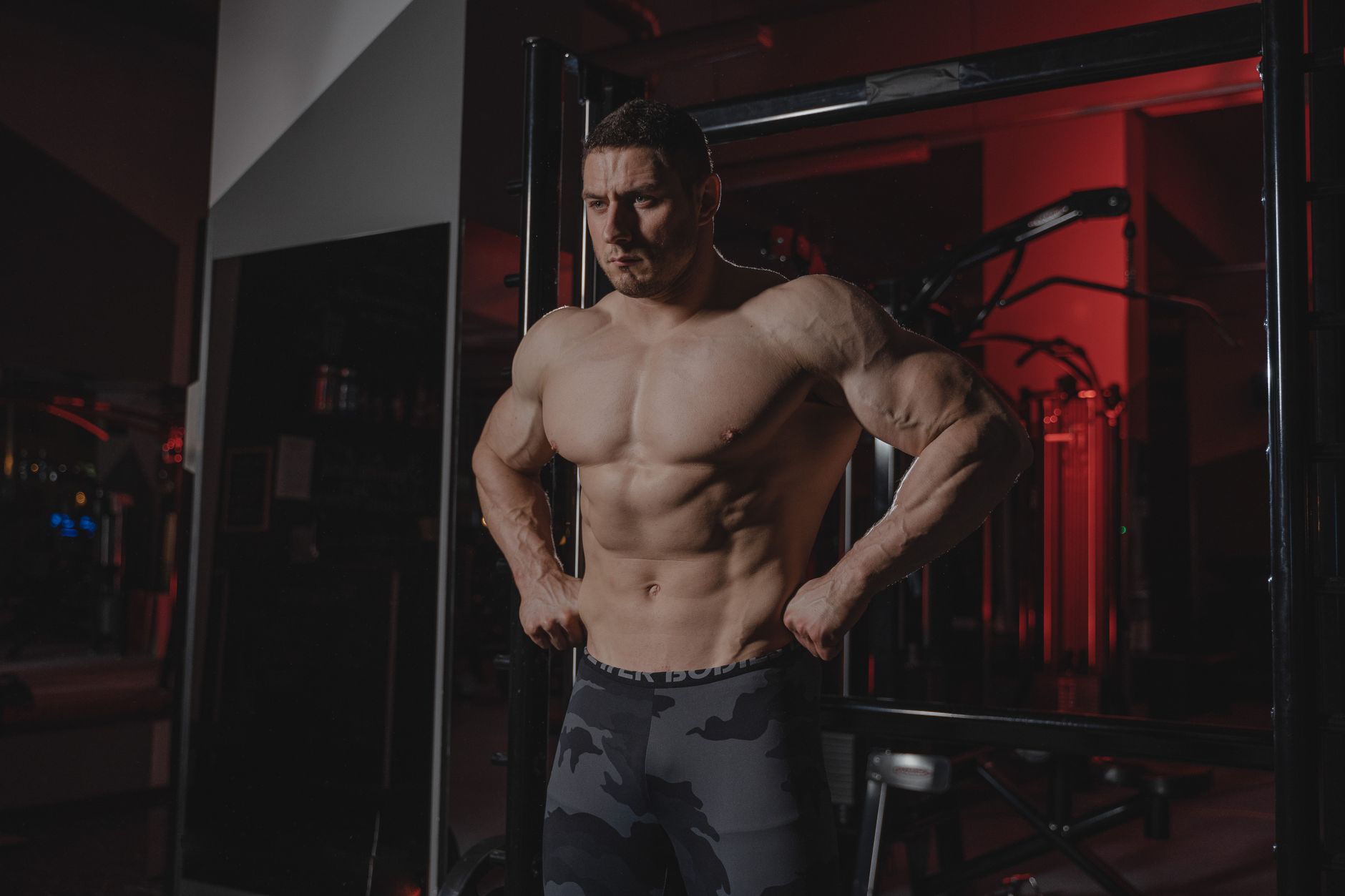 Shirtless bodybuilder flexing muscles under dramatic gym lighting. Fitness and strength.